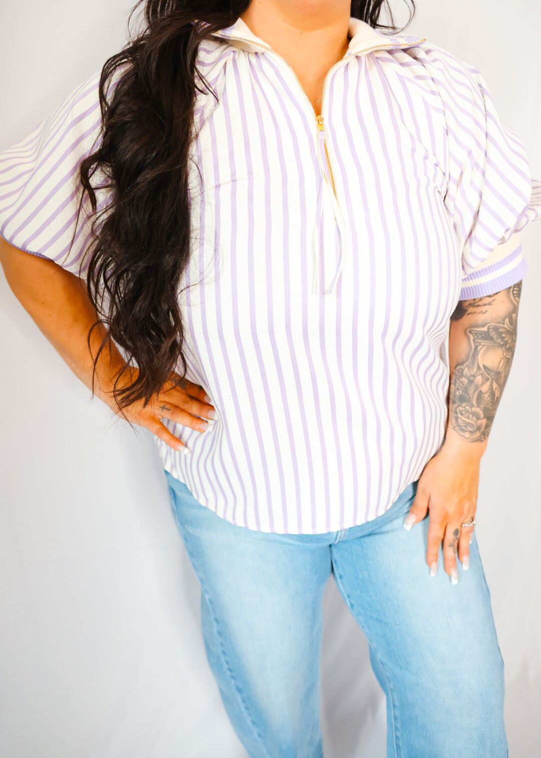 Person wearing a striped shirt and light blue jeans against a plain background