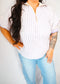 Person wearing a striped shirt and light blue jeans against a plain background