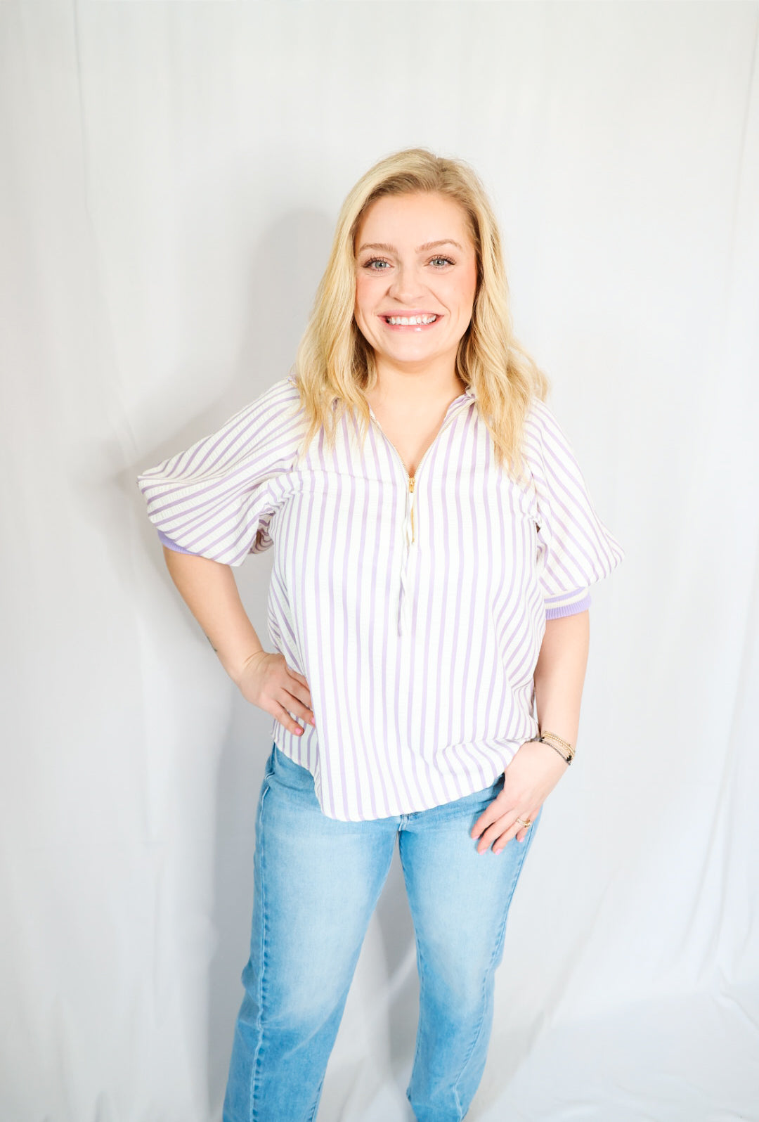 Woman wearing a striped shirt and jeans against a plain background
