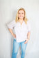 Woman wearing a striped shirt and jeans against a plain background