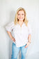Woman wearing a striped shirt and jeans against a plain background