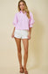 Woman wearing a pink striped shirt and white shorts on a beige background