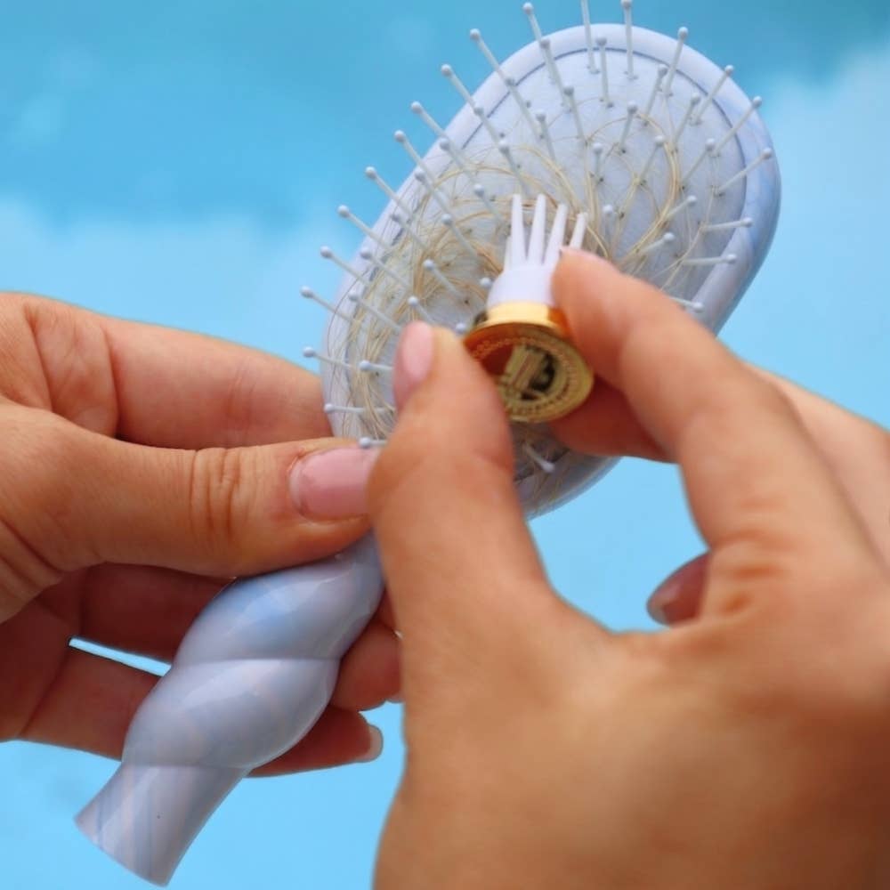 Person holding a hairbrush with a blue background