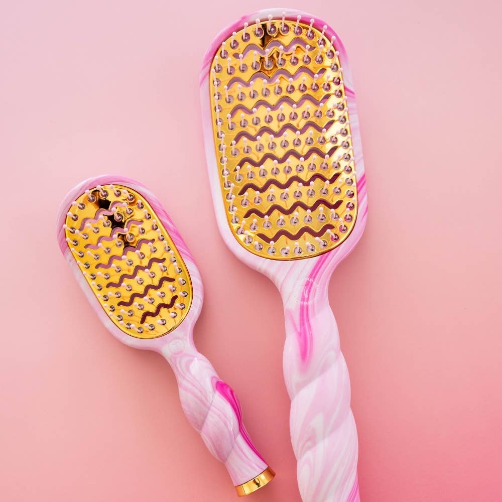 Pink and gold hairbrushes with decorative patterns on a pink background