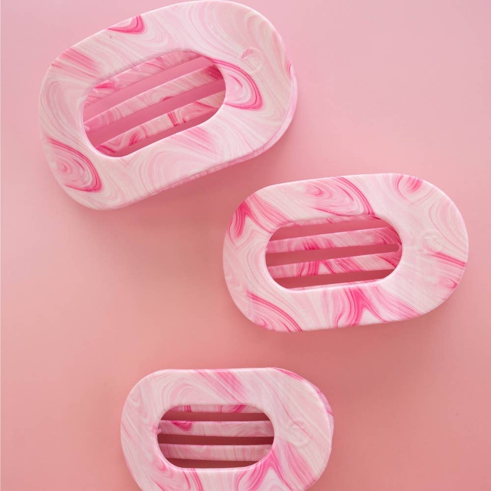 Three pink and white marbled hair clips  on a pink background