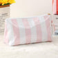 Pink and white striped pouch on a light surface with text in the background