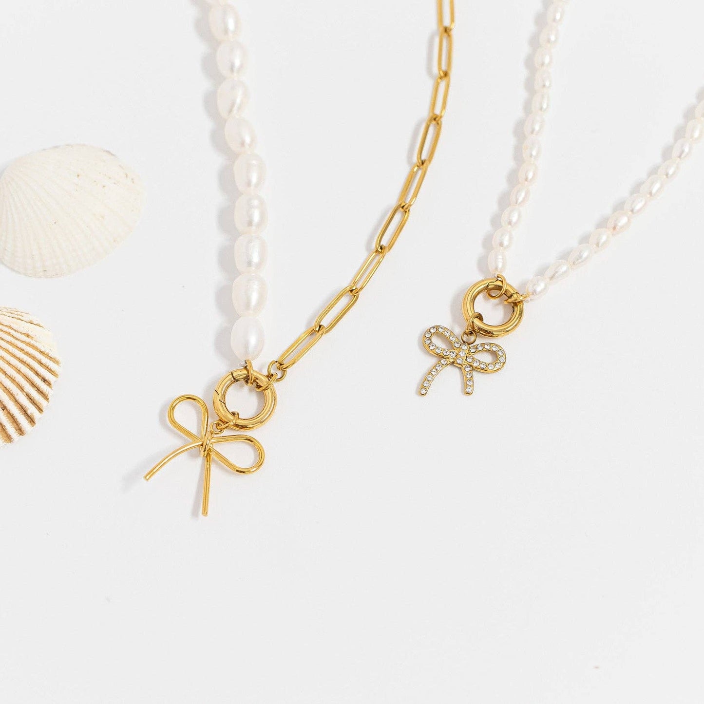 Two pearl necklaces with gold bow charms on a white background