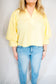 Person wearing a yellow blouse and light wash blue jeans against a plain background