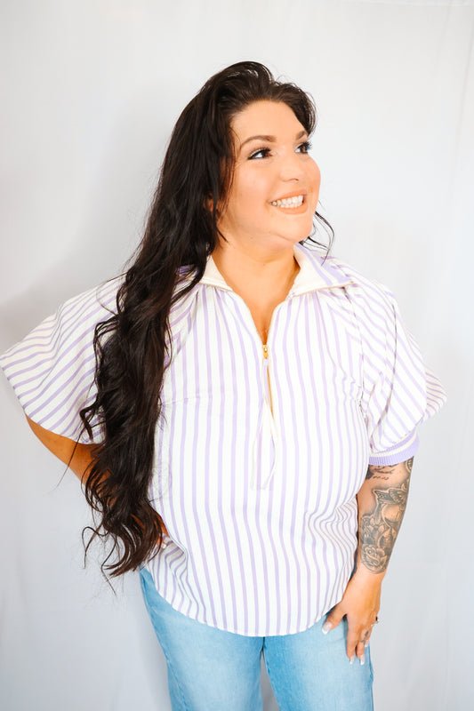 Woman wearing a striped shirt and jeans against a plain background