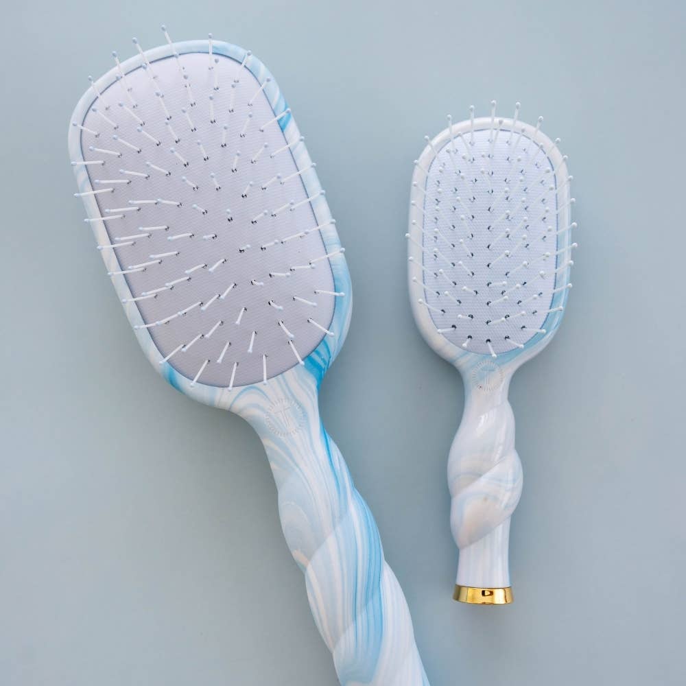 Two hairbrushes with marble-like handles on a light gray background