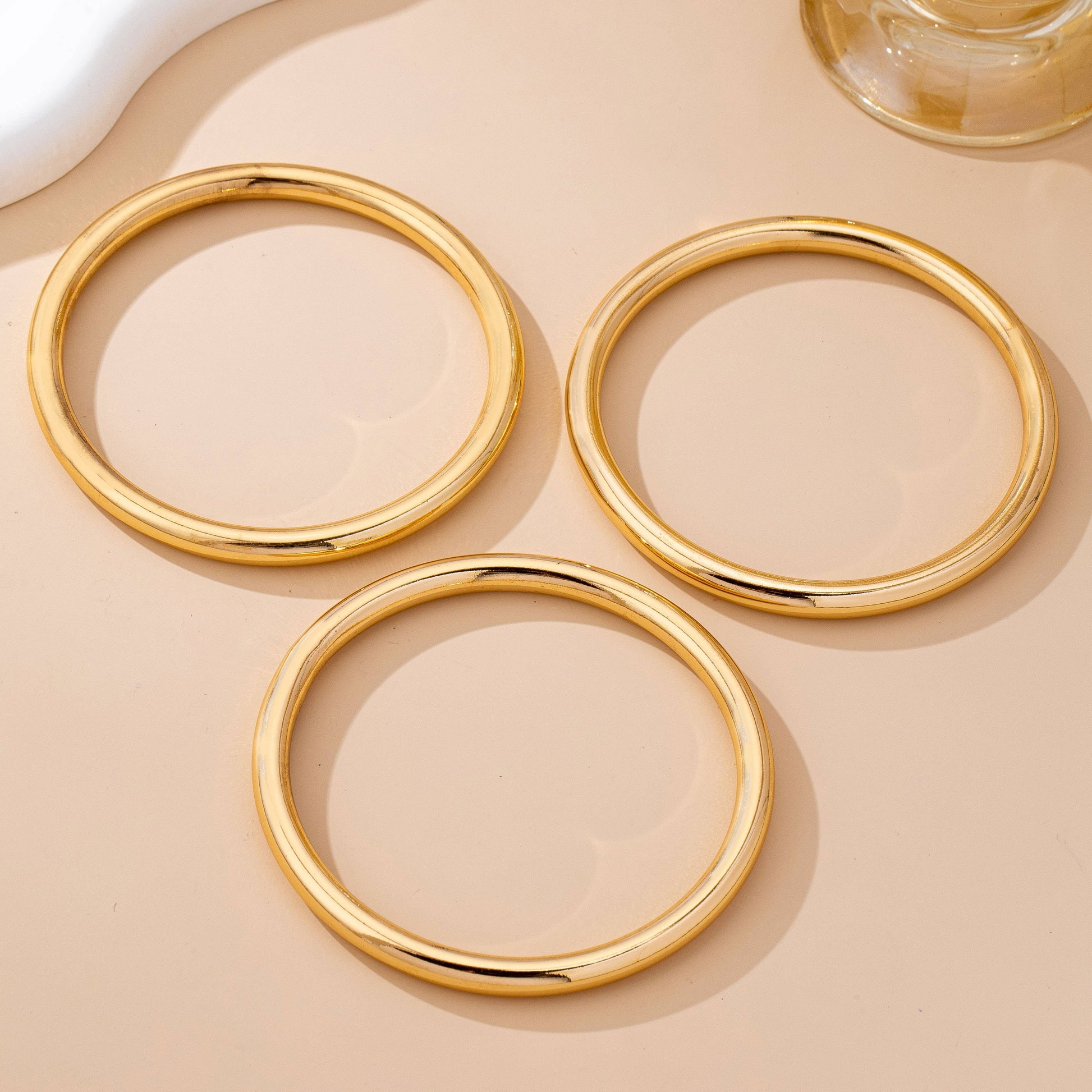 Three gold circular coasters on a beige surface