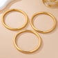 Three gold circular coasters on a beige surface