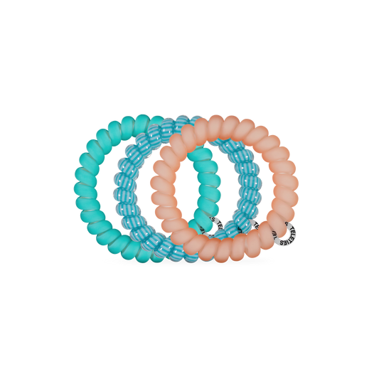 Set of three turquoise and peach-colored hair ties on a white background