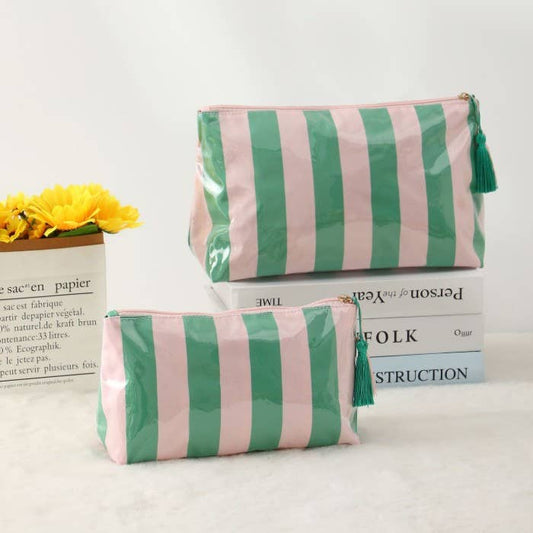 Two green and pink striped pouches on a white surface with books and yellow flowers in the background.
