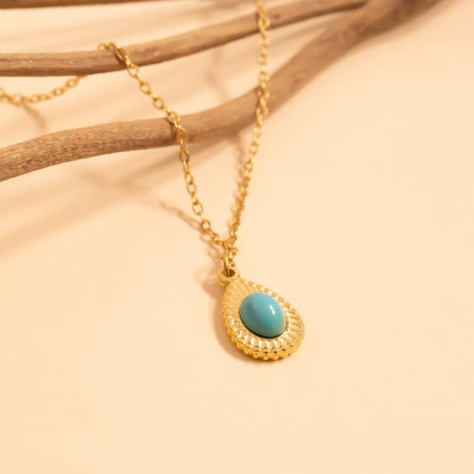 Gold necklace with a turquoise pendant on a beige background