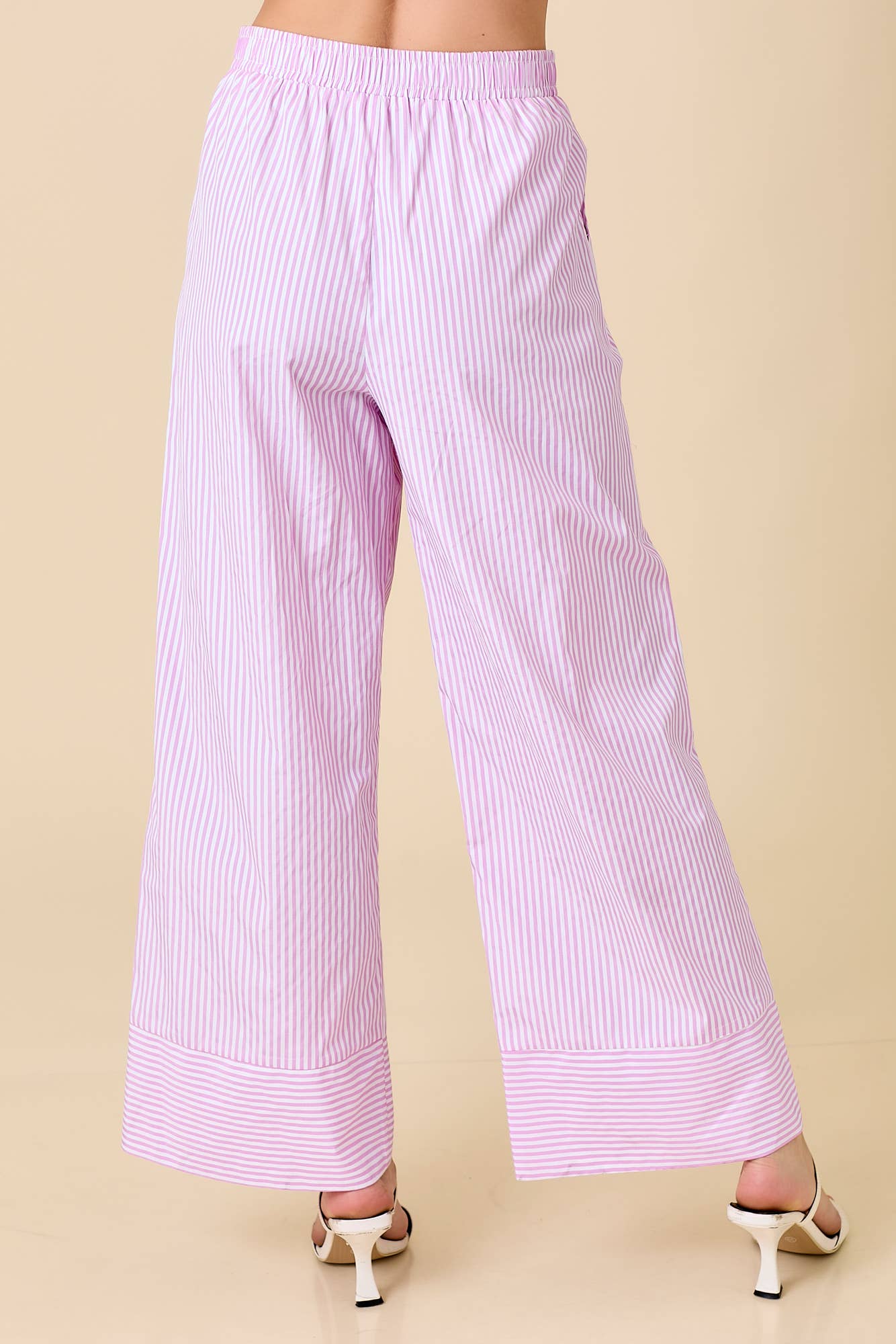 Pink striped pants worn by a person on a beige background